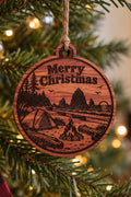 Two Makers Crew West Coast Camping Christmas Ornament — Coastal campsite scene with tent, campfire, sea stacks, evergreens and Merry Christmas greeting